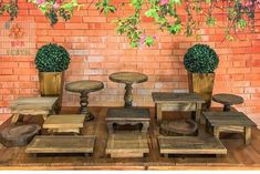 there are several wooden tables and stools in front of a brick wall with potted plants