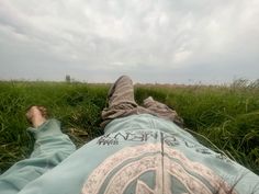 a person laying in the grass with their feet up on his back and one hand behind him