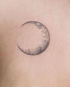 a small crescent tattoo on the back of a woman's chest, it is half moon