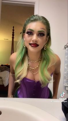 a woman with green hair and makeup is taking a selfie in front of a mirror