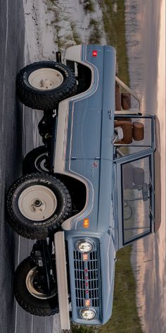 an old blue truck is parked on the side of the road with two tires attached to it