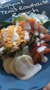 a blue plate topped with veggies covered in ranch dressing next to a hand