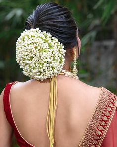 the back of a woman's head with flowers in her hair and necklace on