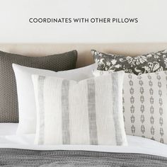 a bed topped with pillows and blankets next to a wall mounted sign that reads coordinatess with other pillows