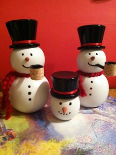 three snowmen are standing next to each other in front of a red painted wall