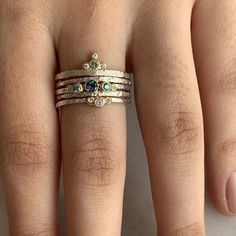 a woman's hand with three different rings on top of her fingers and the other two