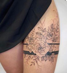 a woman's thigh with flowers on it and a black ribbon around the leg