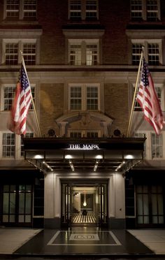 an entrance to the mark hotel at night with american flags flying in the wind and onlookers