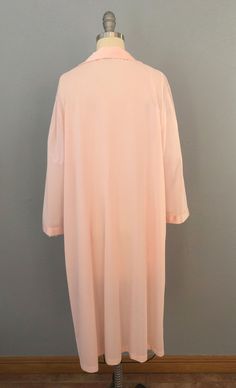 "Vintage robe from the 60's era!! Super soft, silky nylon in a pink-peachy color. Gorgeous appliqued floral embroidery. Collared open v-neck with buttondown front and fabric-covered buttons. Long bell sleeves. One hip pocket. Ankle length. Curl up, and just relax in this sweet robe! Fits a large frame but please double-check the measurements below to ensure the best fit for you. -- M E A S U R E M E N T S --- Bust: 46\" Waist: 48\" HIps: 50\" Shoulders: 17.5\" Length: 43\" Fabric: Dacron polyest Feminine Long Sleeve Robe For Daywear, Long Spring Sleepwear, Pink Robe For Spring Sleepwear, Pink Robe For Sleep And Spring Season, Pink V-neck Spring Robe, Long Sleeve Pink Nightgown For Spring, Pink Feminine Robe For Sleepover, Feminine Pink Robe For Sleepover, Pink Spring Robe For Loungewear