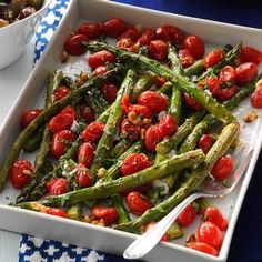 asparagus and cherry tomatoes in a white dish on a blue and white tablecloth