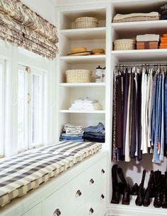 an organized closet with clothes and shoes on the shelves, along with a bench in front of it