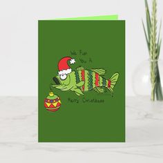 a green christmas card with a fish wearing a santa hat