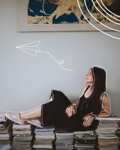 a woman sitting on top of a bed next to a pile of books and papers