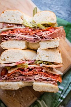 a pile of sandwiches sitting on top of a wooden cutting board