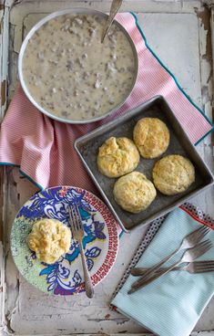 some biscuits are on a plate next to a bowl of soup and a fork with a spoon in it