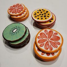 four decorated cookies sitting on top of a white table next to orange slices and kiwis