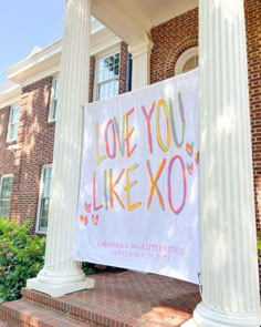 a sign that says love you like xo on the side of a building with columns