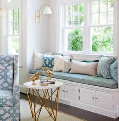 a living room filled with furniture and pillows on top of a window sill next to a table