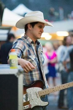 a man with a cowboy hat playing an electric guitar