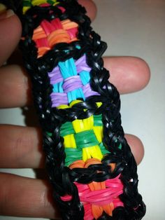 a hand holding a multicolored bracelet made out of rubber bands and plastic beads