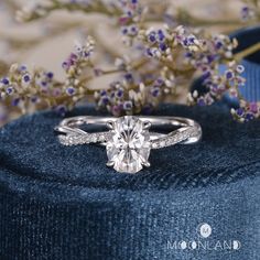 a diamond ring sitting on top of a blue velvet box next to some purple flowers