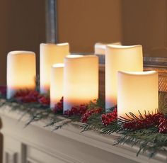 lighted candles are lined up on a mantel