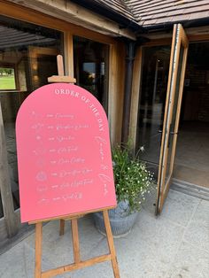 a pink sign with writing on it in front of a building that says order of the day