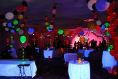 a room filled with lots of tables covered in white tablecloths and colorful balloons