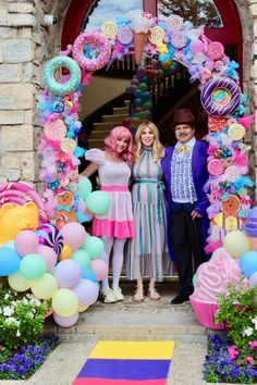 three people standing in front of an entrance decorated with balloons and streamers for a birthday party