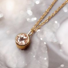 A classic, romantic bezel set morganite necklace. The soft color goes from clear pink to lovely peach depending on the light. Sparks of light shoot from the 16" diamond cut cable chain.  Solid 14k Gold Pendant: The stone is 5.25mm, 1/2 ct. Length including jumpring ~ 9mm Depth of bezel setting ~ 3mm Spring Ring Closure ~ 4mm Solid 14k Gold Chain ~ 16" Diamond cut 1.1 mm width Free insured domestic shipping. Dainty Rose Gold Necklaces With Bezel Setting, Pink Necklace With Bezel Setting For Gift, Pink Gold Gemstone Pendant Necklace, Minimalist 14k Gold-filled Rose Gold Charm Necklaces, Pink Faceted Pendant, Morganite Necklace, Light Shoot, South Pasadena, Necklace Minimalist