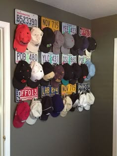 a bunch of hats hanging on the wall in a room with gray walls and white trim