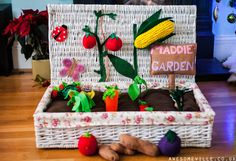 a basket filled with fake vegetables on top of a hard wood floor next to a sign that says haddie garden