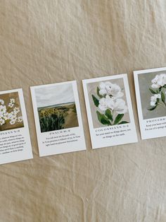 four cards with pictures of flowers on them sitting on a bed sheet in front of a pillow