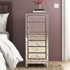 a mirrored chest of drawers with flowers on top in a bedroom next to a bed