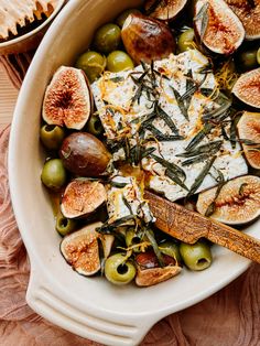 a white bowl filled with olives, cheese and other food on top of a table