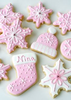 pink and white cookies decorated with snowflakes, mittens, and stocking caps