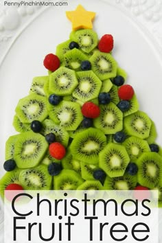 a christmas fruit tree made out of kiwis and raspberries on a white plate