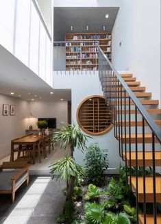 a staircase leading to the second floor with bookshelves and plants on either side