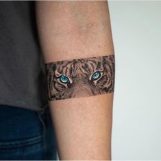 a woman's arm with a tiger and blue eyes tattoo on the left forearm