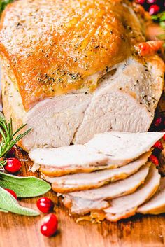 sliced turkey on a cutting board with cranberries and greenery