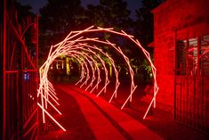 red light streaks on the ground in front of a brick wall and gate at night