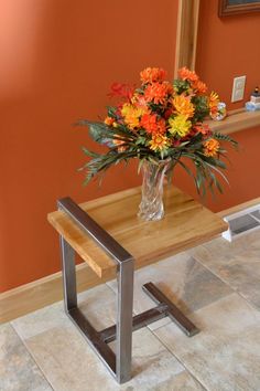 a vase filled with flowers sitting on top of a wooden table next to a mirror