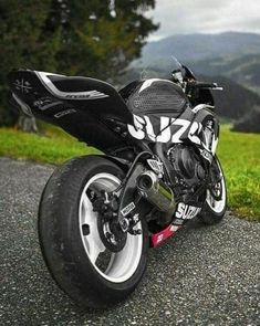 a black and white motorcycle parked on the side of a road next to some grass