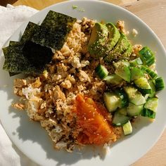 a white plate topped with rice and veggies on top of a wooden table