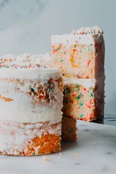 a cake with white frosting and colorful sprinkles on the top is being cut by a knife