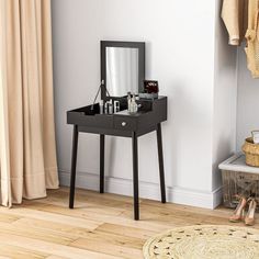 a black vanity table with a mirror and some shoes on the floor next to it