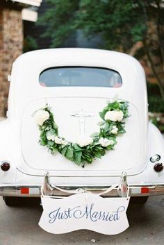 an old white car with a wreath on the back door and just married sign attached to it