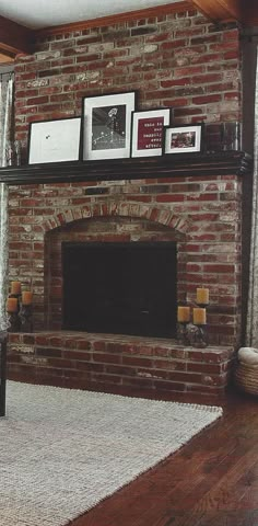 a living room with a brick fireplace and pictures on the mantle above it, along with candles