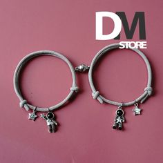 two bracelets with charms on them are displayed against a pink background and the words dm store