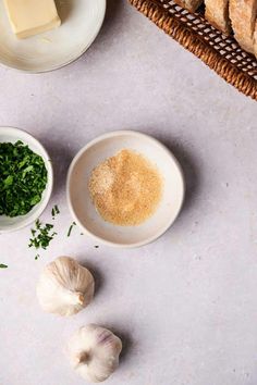 garlic, parsley and butter on a table next to some bread slices in bowls